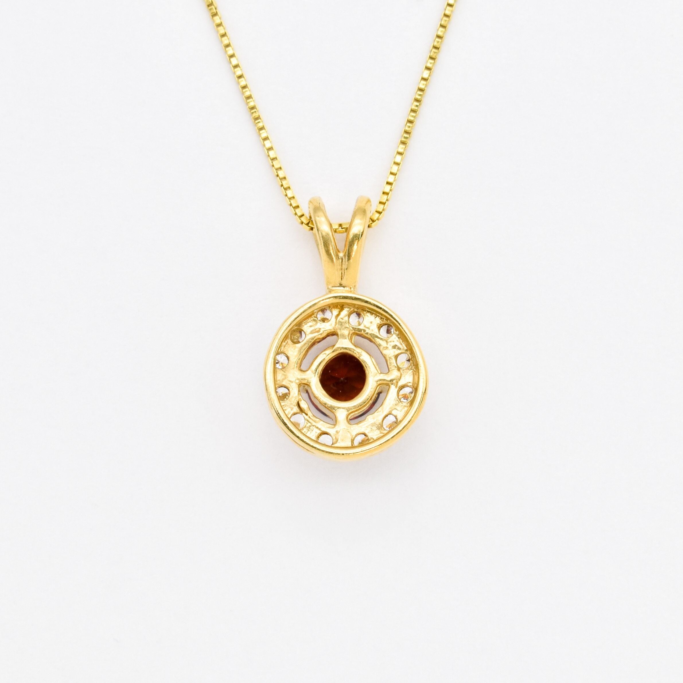 18k yellow gold necklace set with Red Garnet January birthstone, in round cut and prong setting, surrounded with small CZ diamonds. Dainty natural garnet pendant that boosts confidence, enhances courage, and inspires love and success. For passion, protection, & vitality.