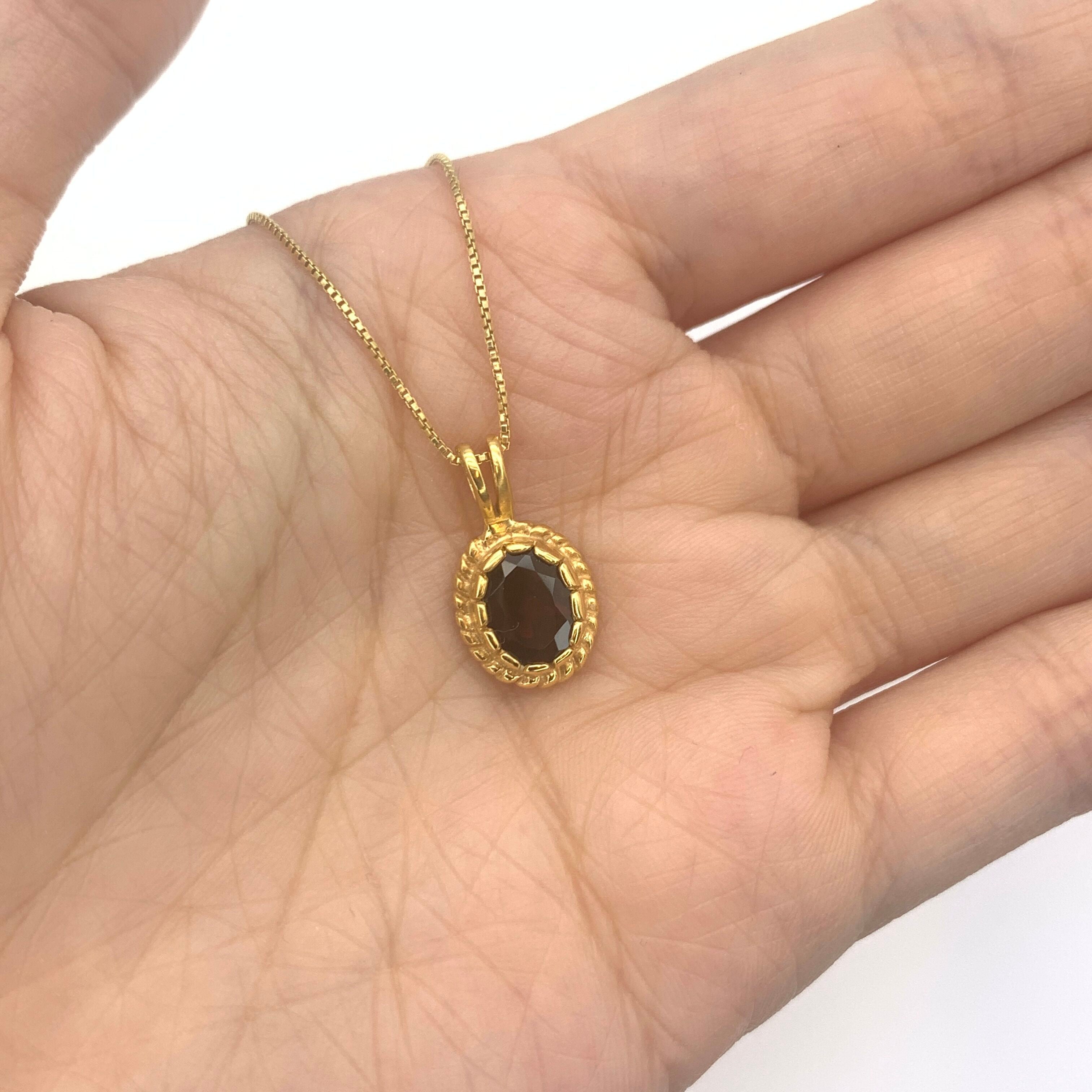 Natural garnet pendant in 18k yellow gold, resting in an open palm – Red solitaire necklace for size reference
