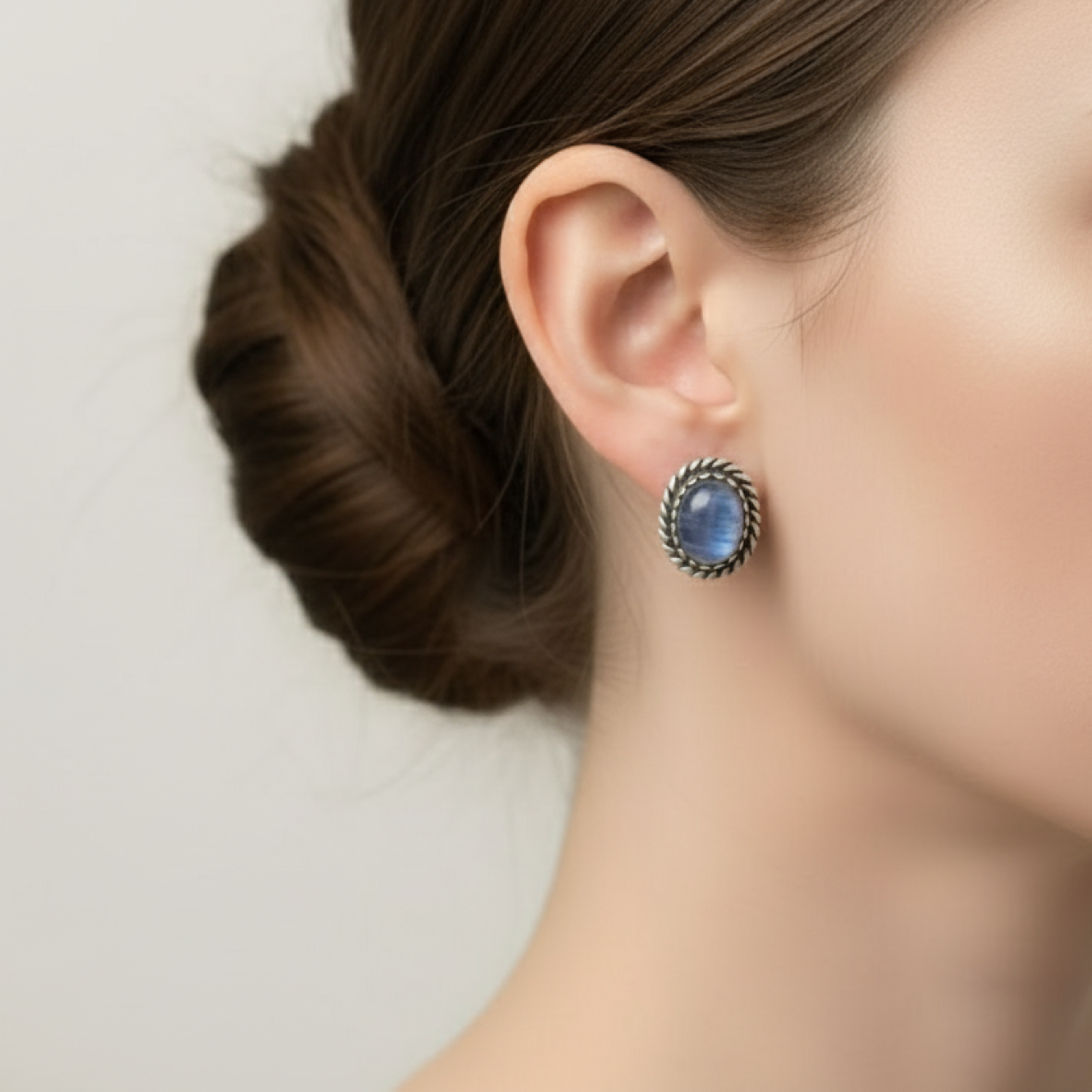 Close-up of oval blue gemstone earrings set in antique silver, perfect for elegant evening wear.