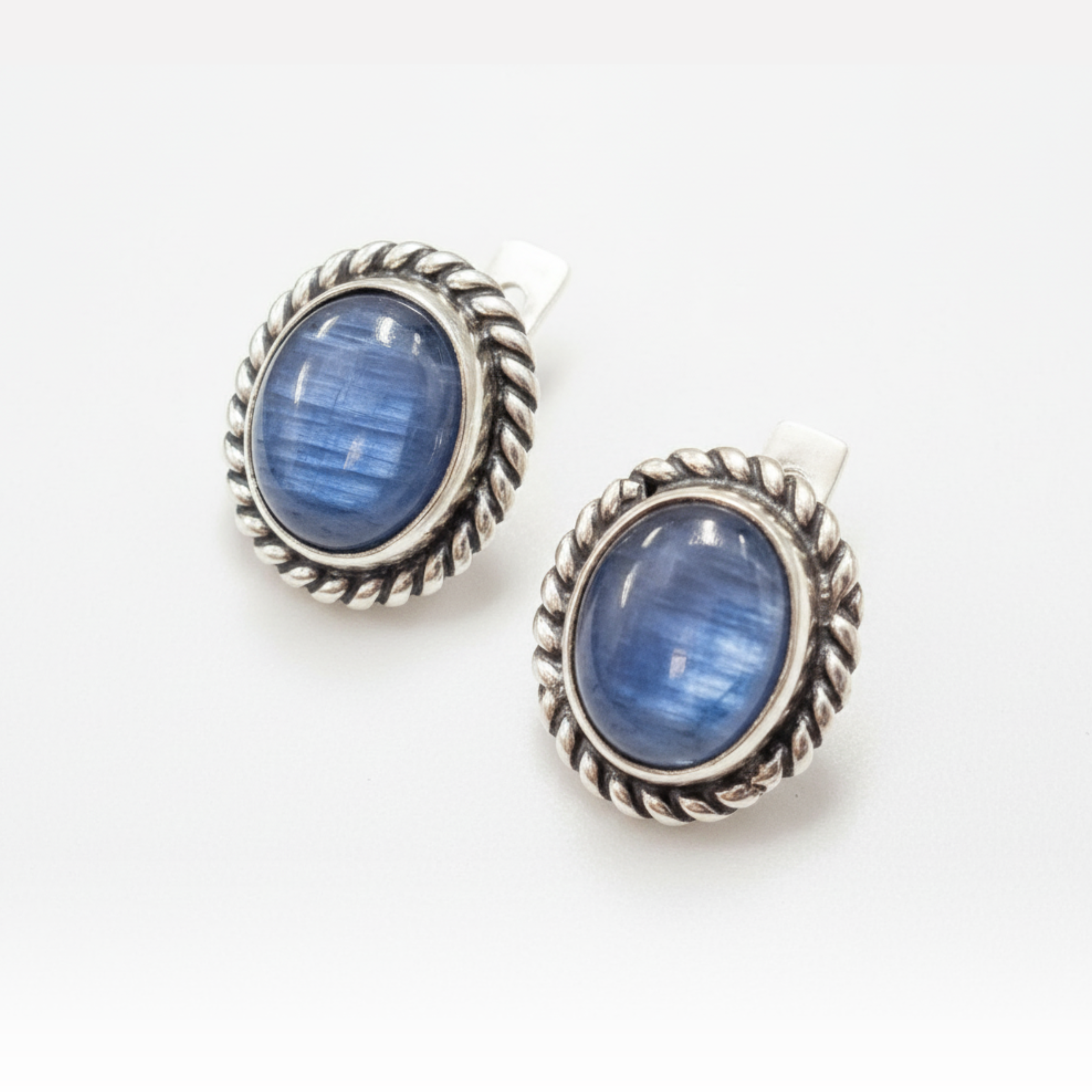 Handcrafted sterling silver earrings featuring polished blue cabochon gemstones with twisted rope design.
