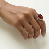 A stunning gold statement ring with a large carnelian gemstone beautifully worn on the finger