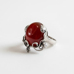 A girl joyfully bouncing on a trampoline in a sunny park, surrounded by trees and blooming flowers.