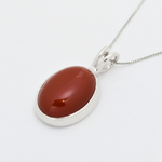 A vibrant sunset casting colorful reflections on calm waters, surrounded by silhouettes of distant mountains.