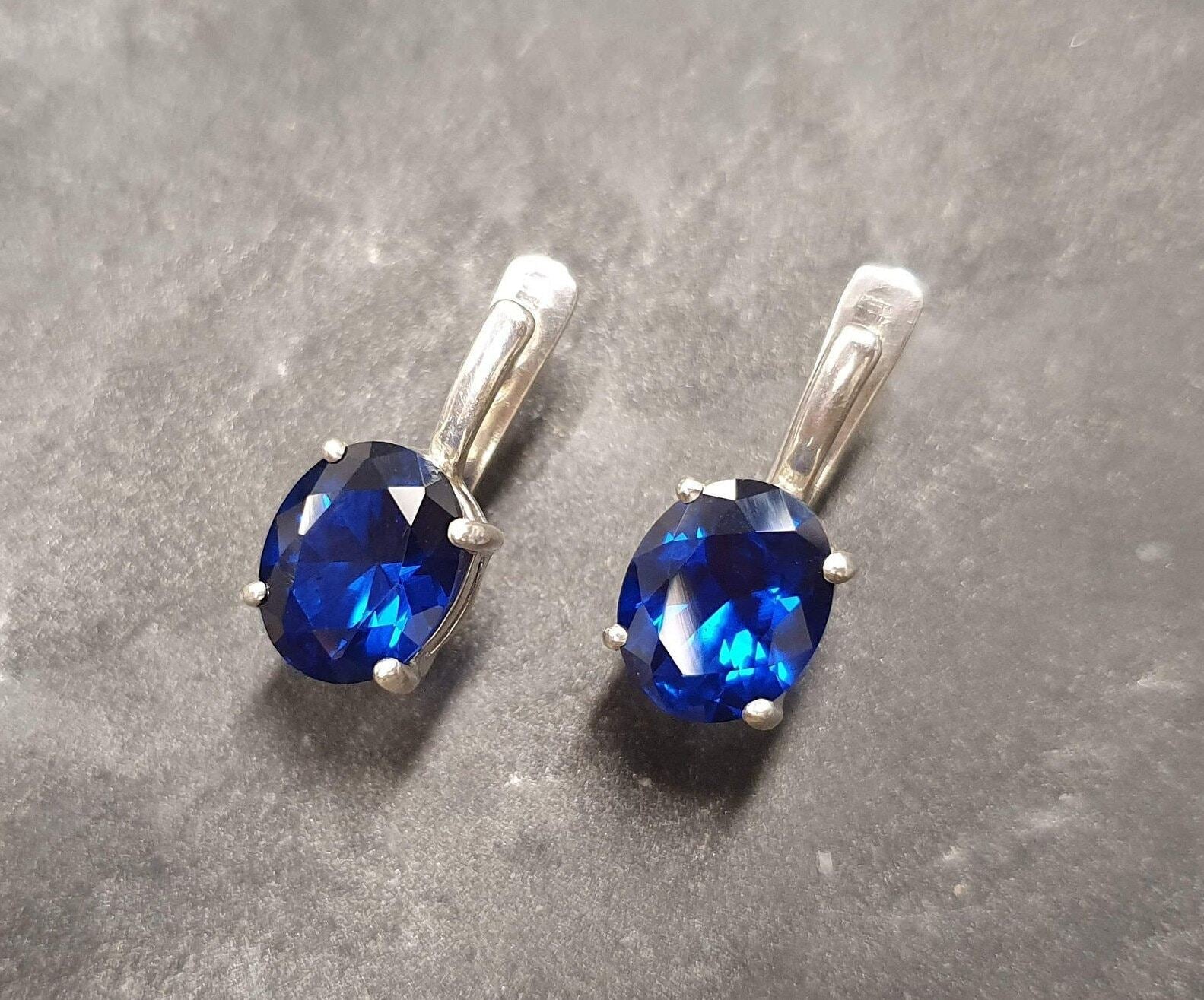 Created Sapphire Earrings made in 925 Sterling Silver with Oval Created Blue Sapphire in Prong setting, September Birthstone gift idea, symbolizes sincerity, truth, and faithfulness, ideal for everyday wear and perfect for birthday gifting and special occasions.