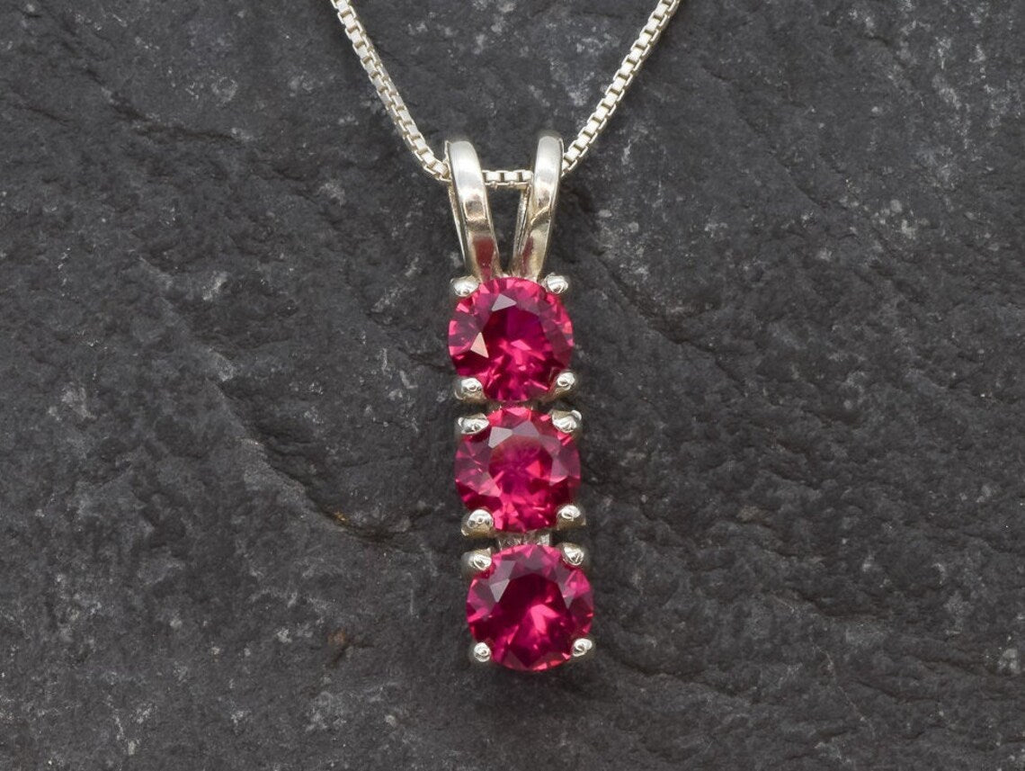 Created Ruby Pendant made in 925 Sterling Silver with Round Created Red Ruby in Three-Stone setting, July Birthstone gift idea, symbolizes nobility, purity, and passion, ideal for everyday wear and perfect for birthday gifting and special occasions.