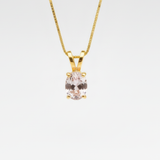 A close-up of a delicate gemstone necklace resting on a soft fabric background, showcasing intricate details and colors.