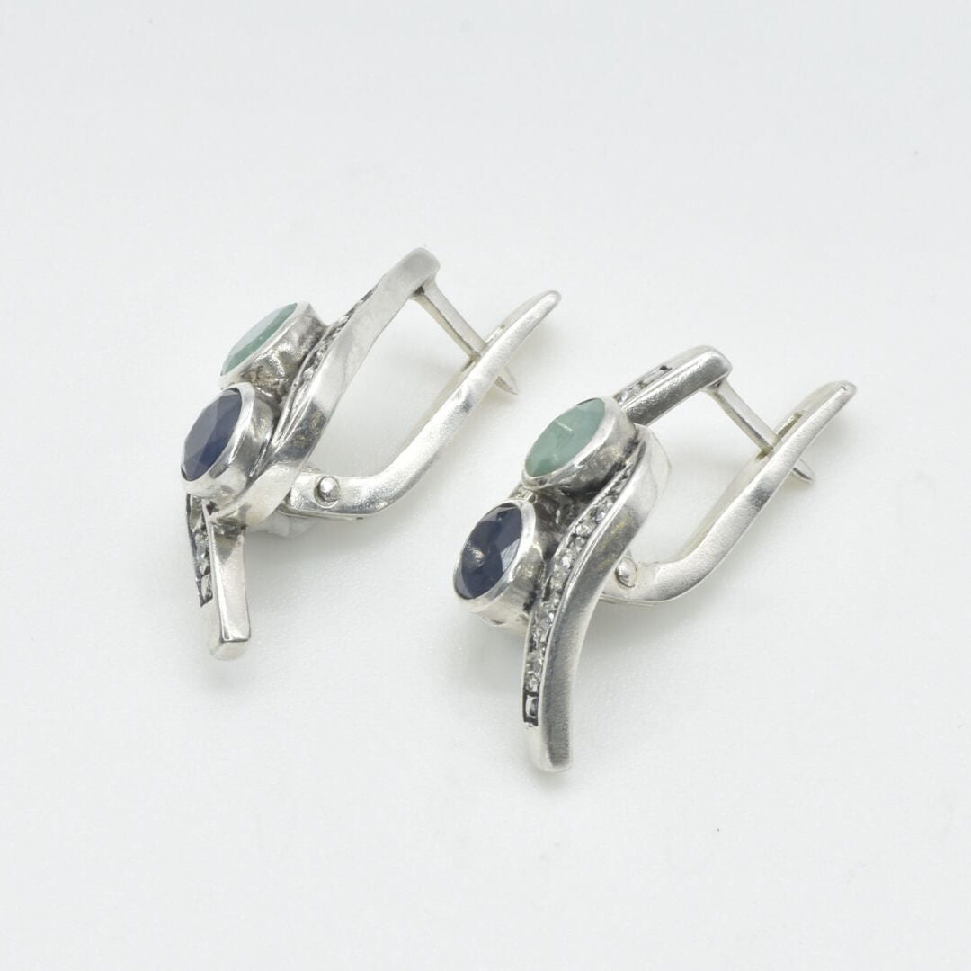 A serene park scene with people enjoying a picnic under the shade of tall trees, surrounded by blooming flowers.