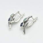 A serene park scene with people enjoying a picnic under the shade of tall trees, surrounded by blooming flowers.