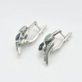 A serene park scene with people enjoying a picnic under the shade of tall trees, surrounded by blooming flowers.