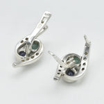 An elegant woman smiling while wearing a stunning Adina Stone necklace, showcasing its intricate design against a soft background.