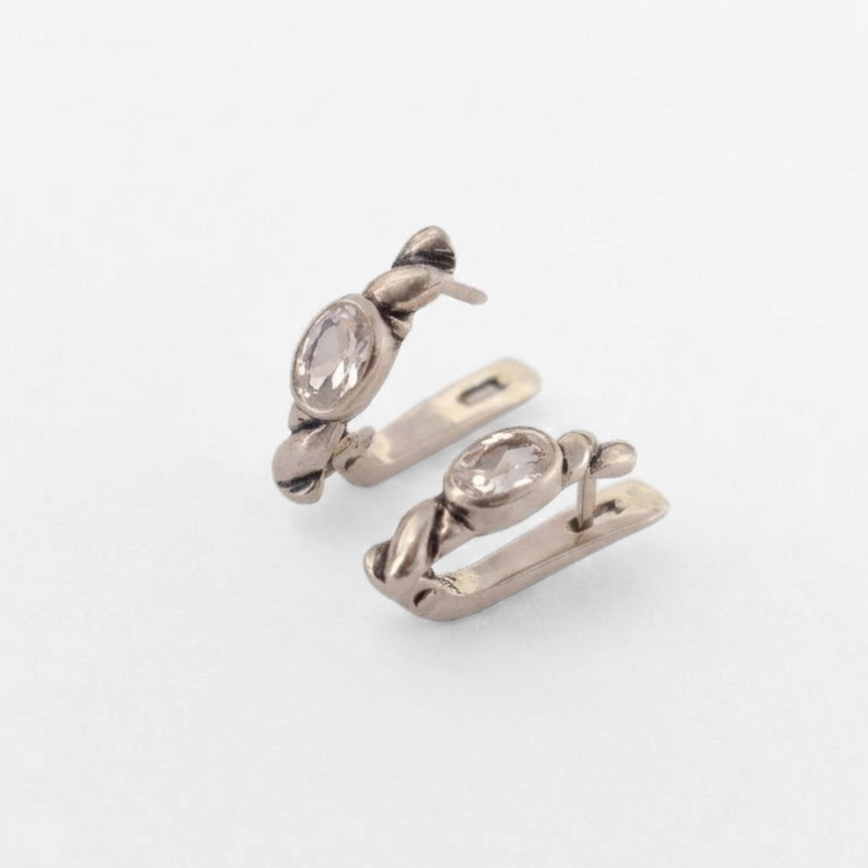 Side view of silver white topaz huggie earrings with hinged closures, oval 6x4mm clear gemstones and antique-inspired rope detail, suited to weddings, anniversaries and gifting; white topaz symbolizes focus and calm.