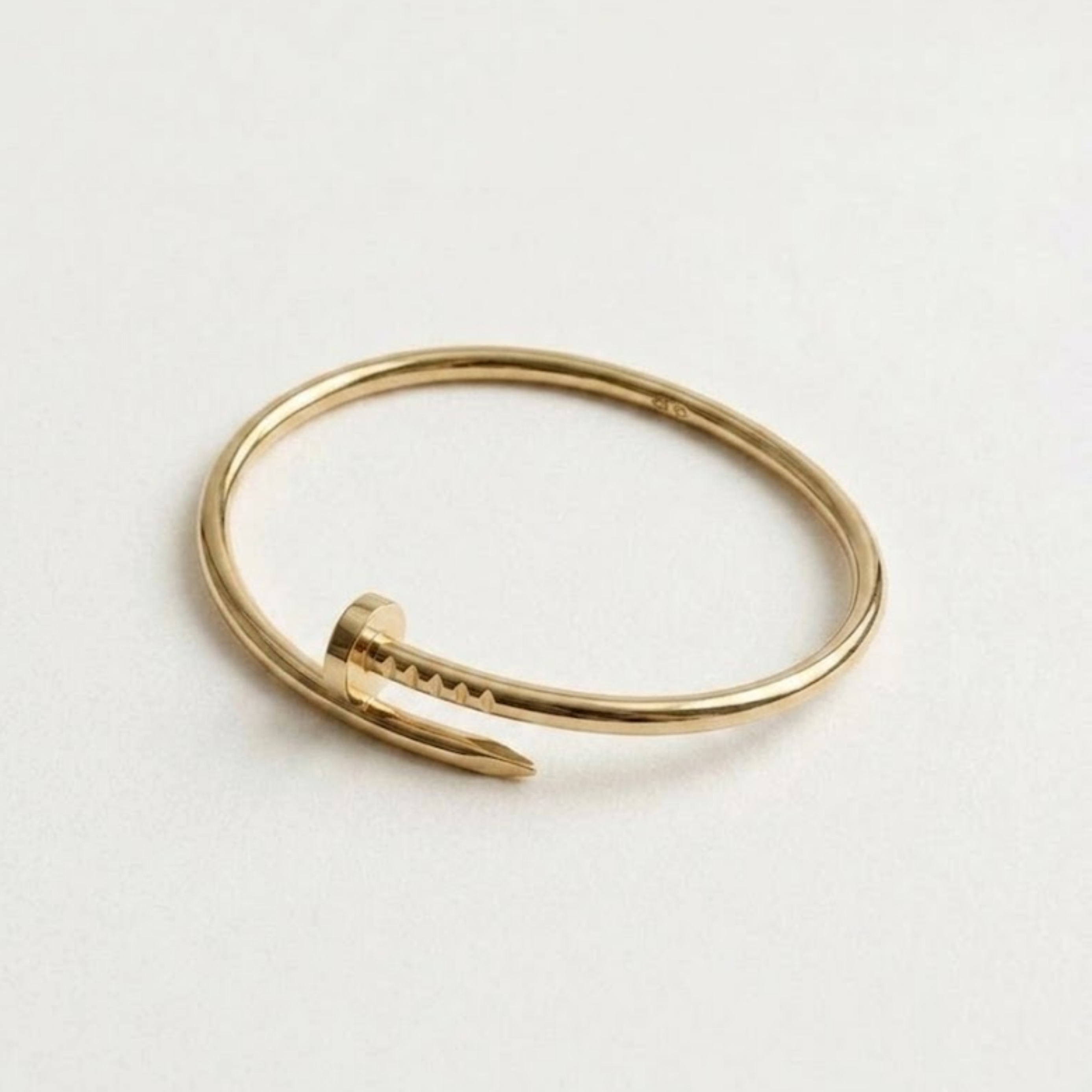 Slim nail cuff in 18k gold vermeil on wrist with layered rings, minimalist bangle ideal for gifting.