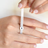 A person's sizing their finger with a plastic ring sizing tool