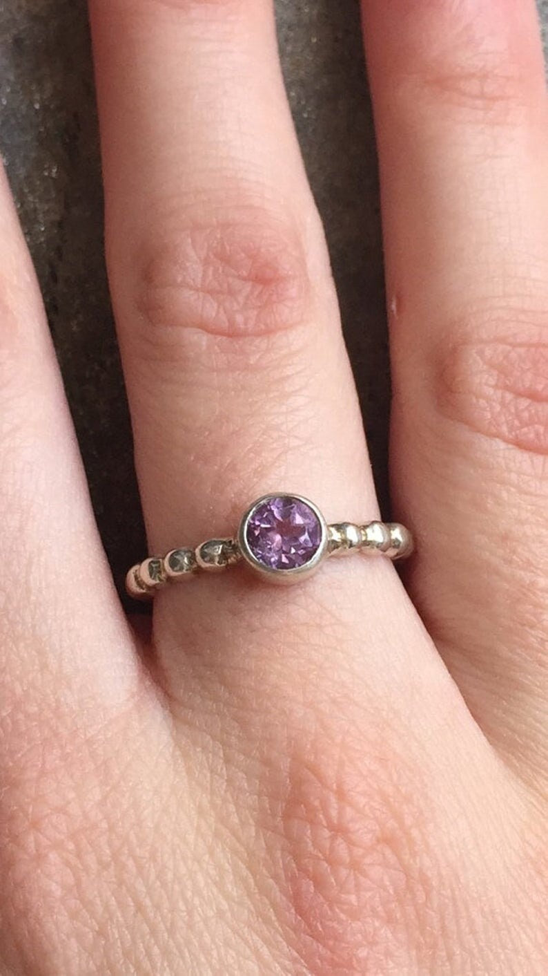 Amethyst Ring styled on index finger with nude nails, showcasing a round bezel setting on a bubble band. A timeless October birthstone piece that brings balance and clarity, suited for daily wear, weekend gatherings, and semi-formal events.