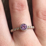 Amethyst Ring styled on index finger with nude nails, showcasing a round bezel setting on a bubble band. A timeless October birthstone piece that brings balance and clarity, suited for daily wear, weekend gatherings, and semi-formal events.