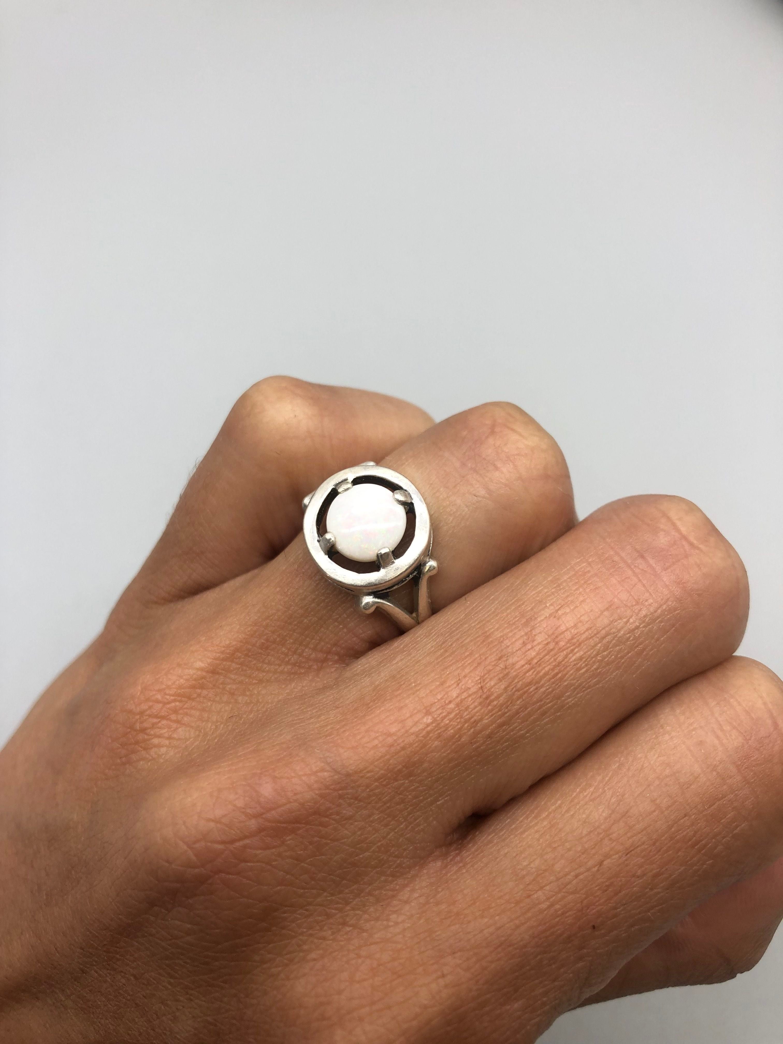 Australian Opal Round Ring worn on ring finger with natural nails. The cabochon opal displays flashes of fire colors set in sterling silver. A meaningful October birthstone piece perfect for birthdays, anniversaries, and promise occasions. Suitable for weddings, dinners, and elegant gatherings.