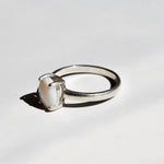 White Opal solitaire ring in sterling silver showcasing flashes of rainbow colors, dainty jewelry style perfect for daily elegance, believed to bring inspiration and emotional balance, a meaningful October birthstone gift idea for anniversaries, engagements, and weddings.