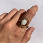 Australian Opal Halo Ring worn on index finger with nude nails, creating a sophisticated look believed to inspire confidence and passion, perfect for evening events and anniversary dinners.
