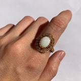 Australian Opal Halo Ring worn on index finger with nude nails, creating a sophisticated look believed to inspire confidence and passion, perfect for evening events and anniversary dinners.