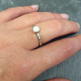 White Opal Bezel Ring worn on middle finger with natural nails. The engraved band adds a boho and tribal touch, while the stone shows subtle flashes of color. A dainty promise ring and October birthstone gift. Perfect for casual outings, summer gatherings, and anniversaries.