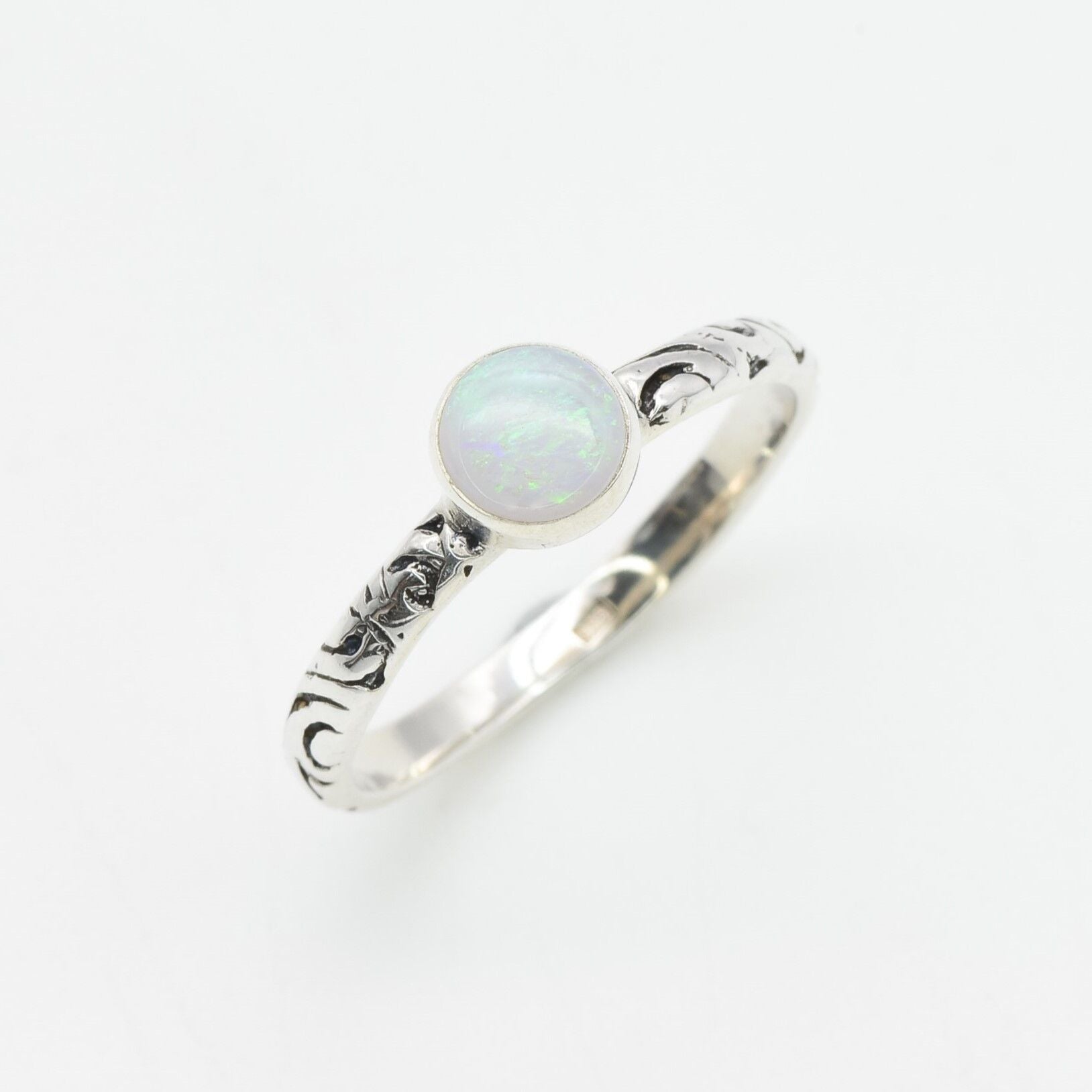 Bezel Opal ring with engraved silver band in a tribal boho style. The opal displays fire colors and flashing rainbow tones, symbolizing hope, creativity and emotional balance. A unique October birthstone gift perfect for anniversaries, festivals, weddings and special celebrations.