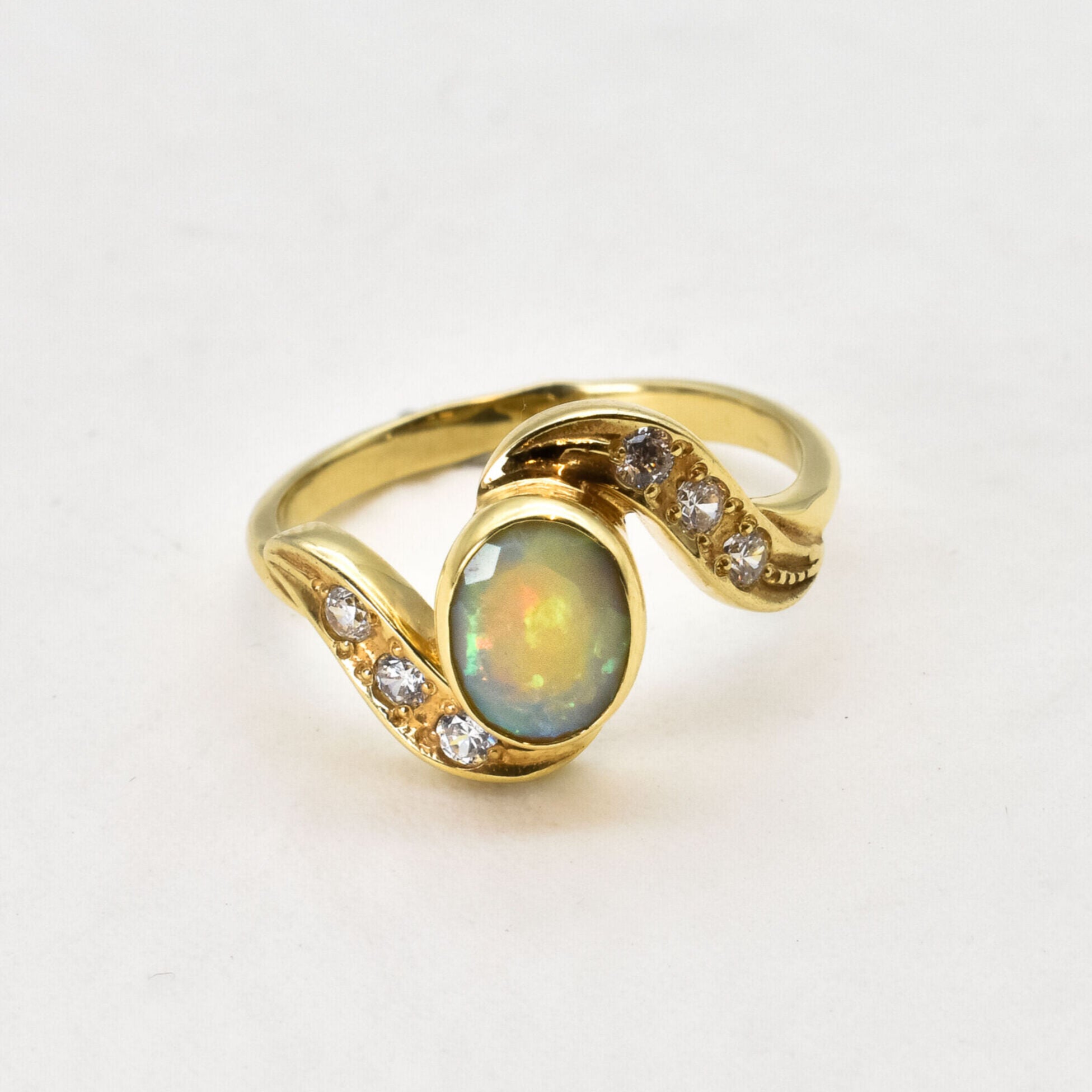 Vintage Opal Ring in a bezel set gold wave design with flashes of rainbow and fire colors, accented by sparkling CZ Diamonds on each curve. Opal is believed to inspire creativity, hope and emotional balance, making it a meaningful October birthstone gift for anniversaries, engagements, weddings and special celebrations.