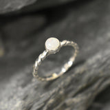 White Opal bezel solitaire ring with round cut stone and twisted band in sterling silver, a timeless jewelry style that highlights flashes of fire colors and durability. Offers the benefit of a secure bezel setting with a refined solitaire look, making it a meaningful October birthstone gift idea. Perfect for birthdays, anniversaries, engagements, and daily wear events.