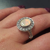 White Opal oval bezel halo ring with Victorian vintage design in solid 925 sterling silver, featuring flashes of fire colors for energy and inspiration, perfect as an October birthstone gift and for engagements, anniversaries, or elegant celebrations.
