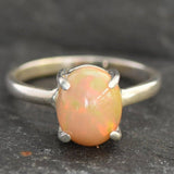 Ethiopian Fire Opal Solitaire Ring in sterling silver with a cabochon cut oval stone showing flashes of fire colors. Opal is linked to creativity, inspiration, and emotional balance, making it a meaningful October birthstone gift. A thoughtful choice for birthdays, anniversaries, promise rings, or engagements. Suitable for daily wear, weddings, and classic elegant occasions.