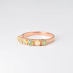 Rose gold half eternity ring with cabochon-cut opals showcasing flashes of fire colors, symbolizing hope and emotional balance, perfect as an October birthstone gift for weddings, anniversaries, or everyday elegance.