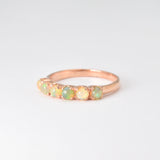 Rose gold half eternity ring with cabochon-cut opals showcasing flashes of fire colors, symbolizing hope and emotional balance, perfect as an October birthstone gift for weddings, anniversaries, or everyday elegance.