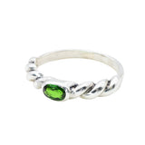 A twisted silver band with a vivid green gemstone, modern and artistic.