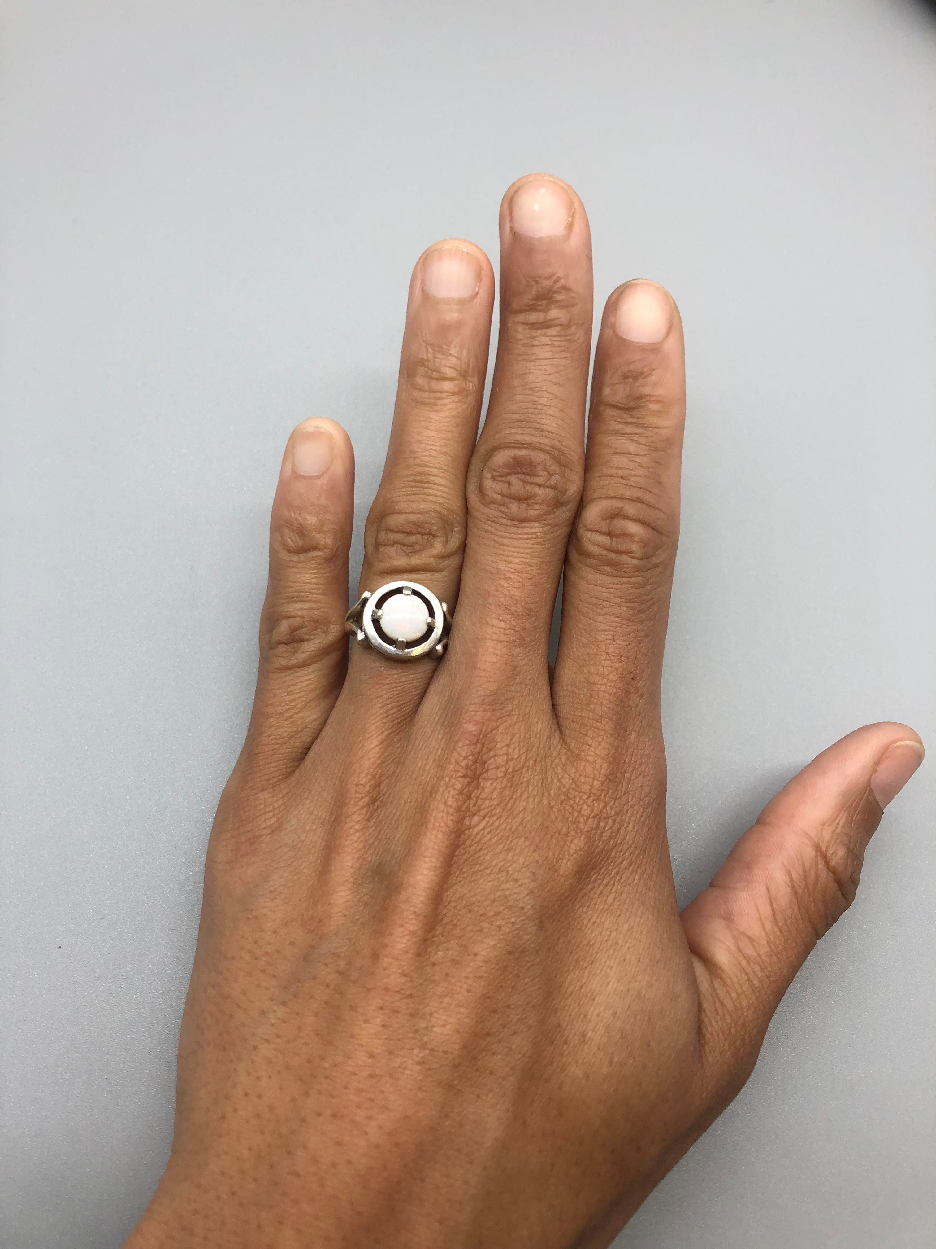 Classic Australian Opal Ring worn on hand with bare nails. Features a round cabochon opal with subtle flashes of fire colors set in sterling silver. A timeless October birthstone ring ideal for promise or engagement gifts, best worn at formal events, anniversaries, and special celebrations.