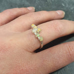 Dainty Fire Opal Cabochon Ring in bypass design worn on index finger with bare nails, glowing with fire colors, styled effortlessly with a black ribbed top, ideal for evening outings, birthday dinners, and festive events.