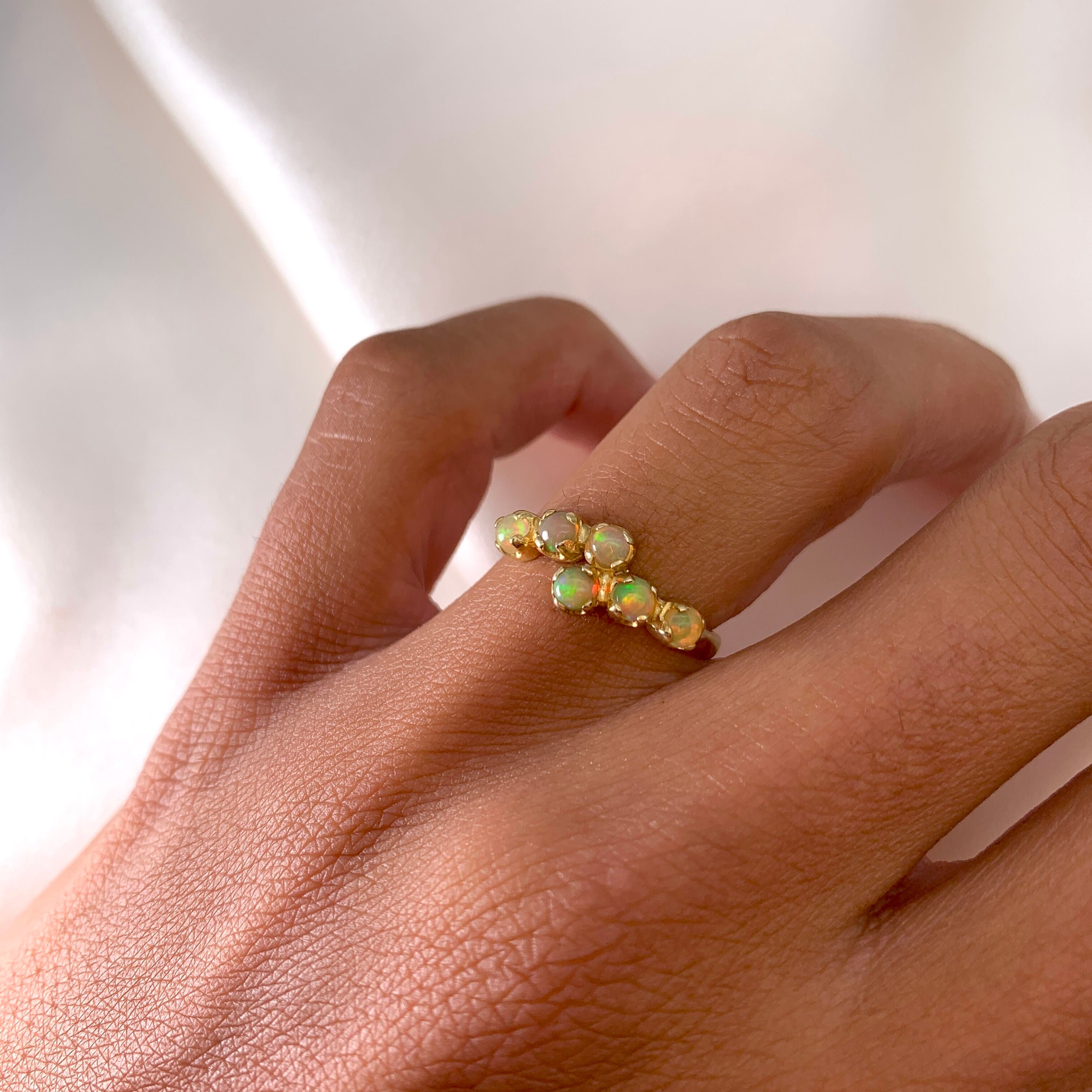 Dainty Opal Six Stone Ring worn on ring finger, featuring a vintage bypass gold setting. Perfect for bringing inspiration and emotional balance, ideal for October birthdays, anniversaries and romantic dinners.
