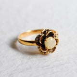 Vintage Fire Opal flower ring with a rose inspired artisan design in gold. The daisy style petals frame a round opal center for a floral and feminine look. Opal is believed to bring hope, creativity and emotional balance, making it a meaningful October birthstone gift. Perfect for weddings, anniversaries, special celebrations and romantic events.