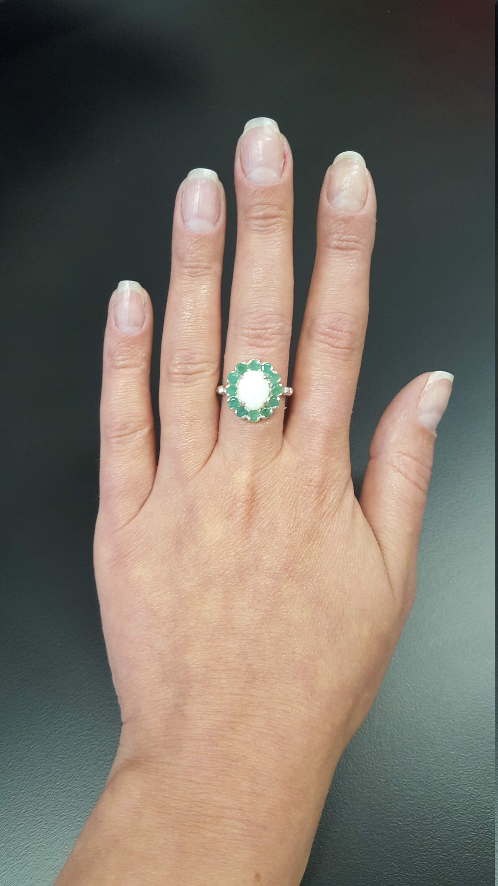 Opal halo floral ring with Genuine Emeralds in a vintage victorian flower halo, White cabochon center, and beaded Bubble Band for a bold statement cocktail look showing flashes of fire colors. Benefits include creativity, harmony, and calm. Ideal October birthstone gift with meaningful May emerald accents.
Worn for weddings, cocktail parties, anniversaries, graduations, garden events, and holiday gatherings.