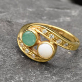 Opal and Emerald Two-Stone Bypass Wave Ring featuring white Opal with flashes of fire colors paired with real green Emerald, accented by CZ pave stones for timeless jewelry style. This design balances elegance with symbolism, making it an ideal October and May birthstone gift idea. Perfect for weddings, anniversaries, cocktail parties, and celebratory events where sophistication is desired.