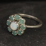 Opal and Emerald Flower Ring in sterling silver with a floral cluster design showing flashes of fire colors from the opal and genuine green emeralds. Opal is the October birthstone linked to inspiration and creativity, while emerald is the May birthstone symbolizing love and harmony, making this a meaningful birthstone gift. A thoughtful present for birthdays, anniversaries, and special occasions. Suitable for daily wear, weddings, dinners, and parties.