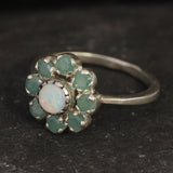 Opal and Emerald Flower Ring in sterling silver with a floral cluster design showing flashes of fire colors from the opal and genuine green emeralds. Opal is the October birthstone linked to inspiration and creativity, while emerald is the May birthstone symbolizing love and harmony, making this a meaningful birthstone gift. A thoughtful present for birthdays, anniversaries, and special occasions. Suitable for daily wear, weddings, dinners, and parties.