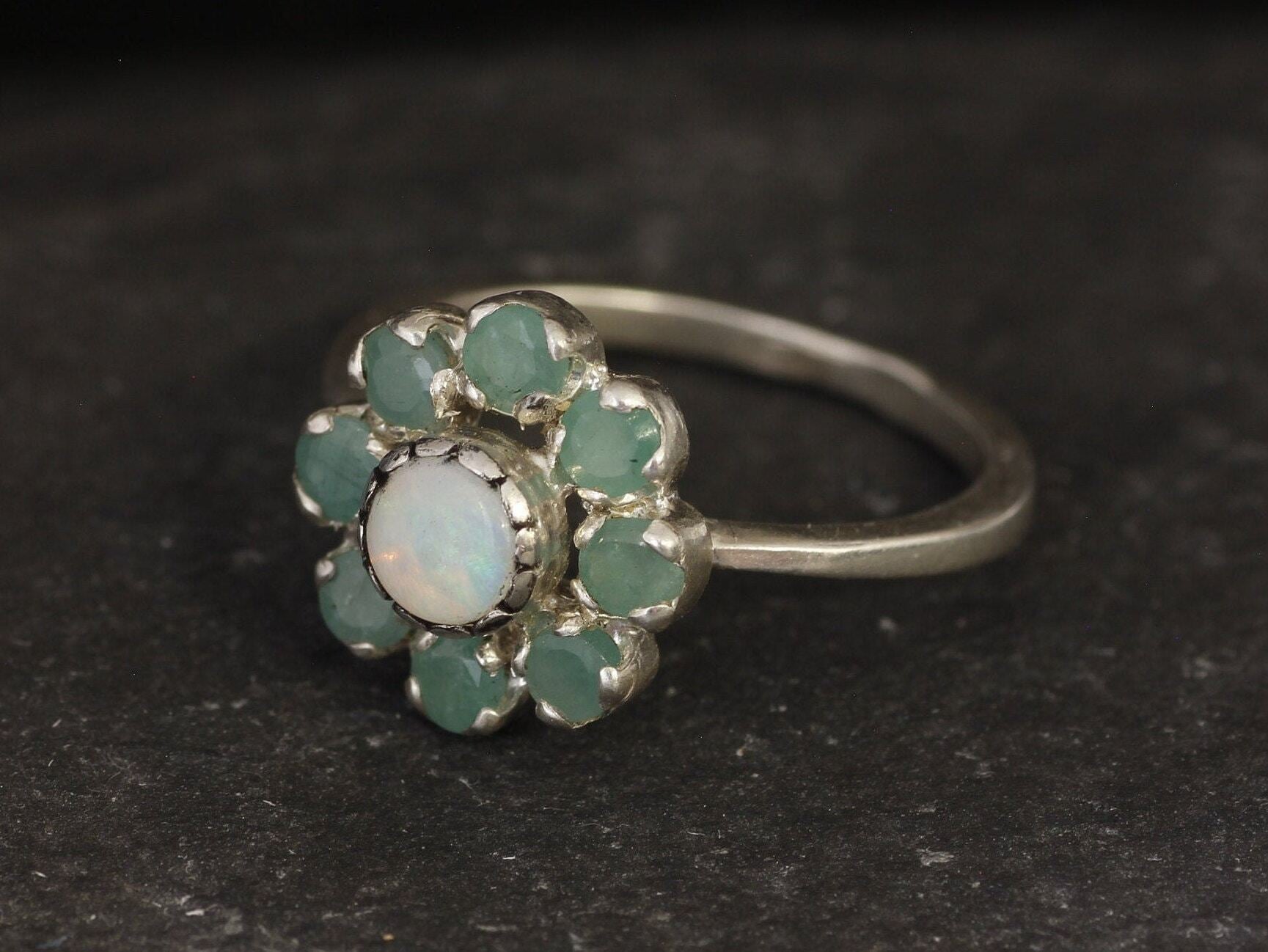 Opal and Emerald Flower Ring in sterling silver with a floral cluster design showing flashes of fire colors from the opal and genuine green emeralds. Opal is the October birthstone linked to inspiration and creativity, while emerald is the May birthstone symbolizing love and harmony, making this a meaningful birthstone gift. A thoughtful present for birthdays, anniversaries, and special occasions. Suitable for daily wear, weddings, dinners, and parties.