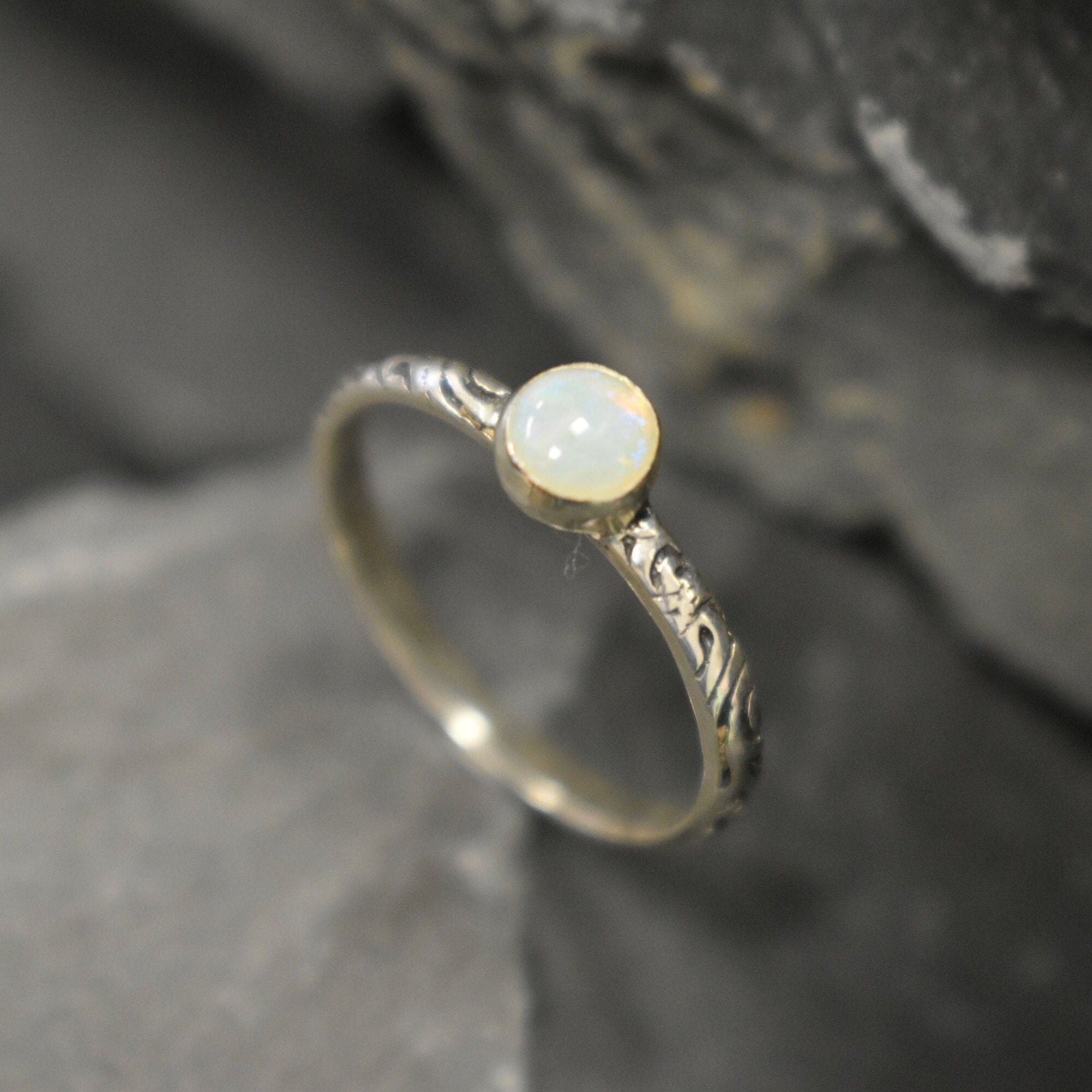 White Opal Bezel Ring with engraved tribal inspired silver band. The dainty minimalist design highlights the gemstone with flashes of color, making it both elegant and unique. Opal is known to bring inspiration, harmony, and emotional balance. A thoughtful promise ring or October birthstone gift for birthdays, anniversaries, and special milestones. Perfect to wear daily or for boho chic events, weddings, and family gatherings.