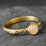 Bezel Opal ring with engraved gold band in a tribal boho style. The opal displays fire colors and flashing rainbow tones, symbolizing hope, creativity and emotional balance. A unique October birthstone gift perfect for anniversaries, festivals, weddings and special celebrations.