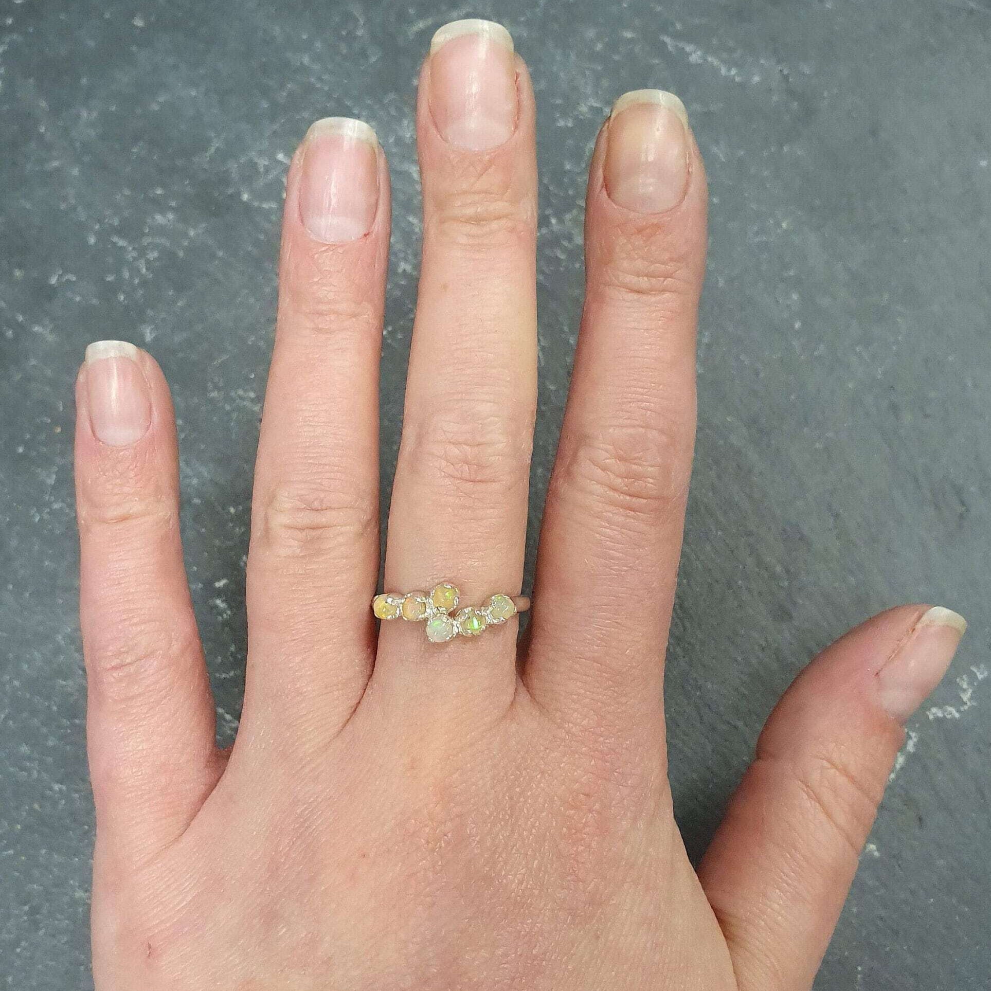 Ethiopian Fire Opal Bypass Ring with cabochon gems worn on middle finger with natural nails, radiating flashes of fire colors, styled with minimalistic outfits, perfect for office gatherings, cocktail parties, and wedding receptions.