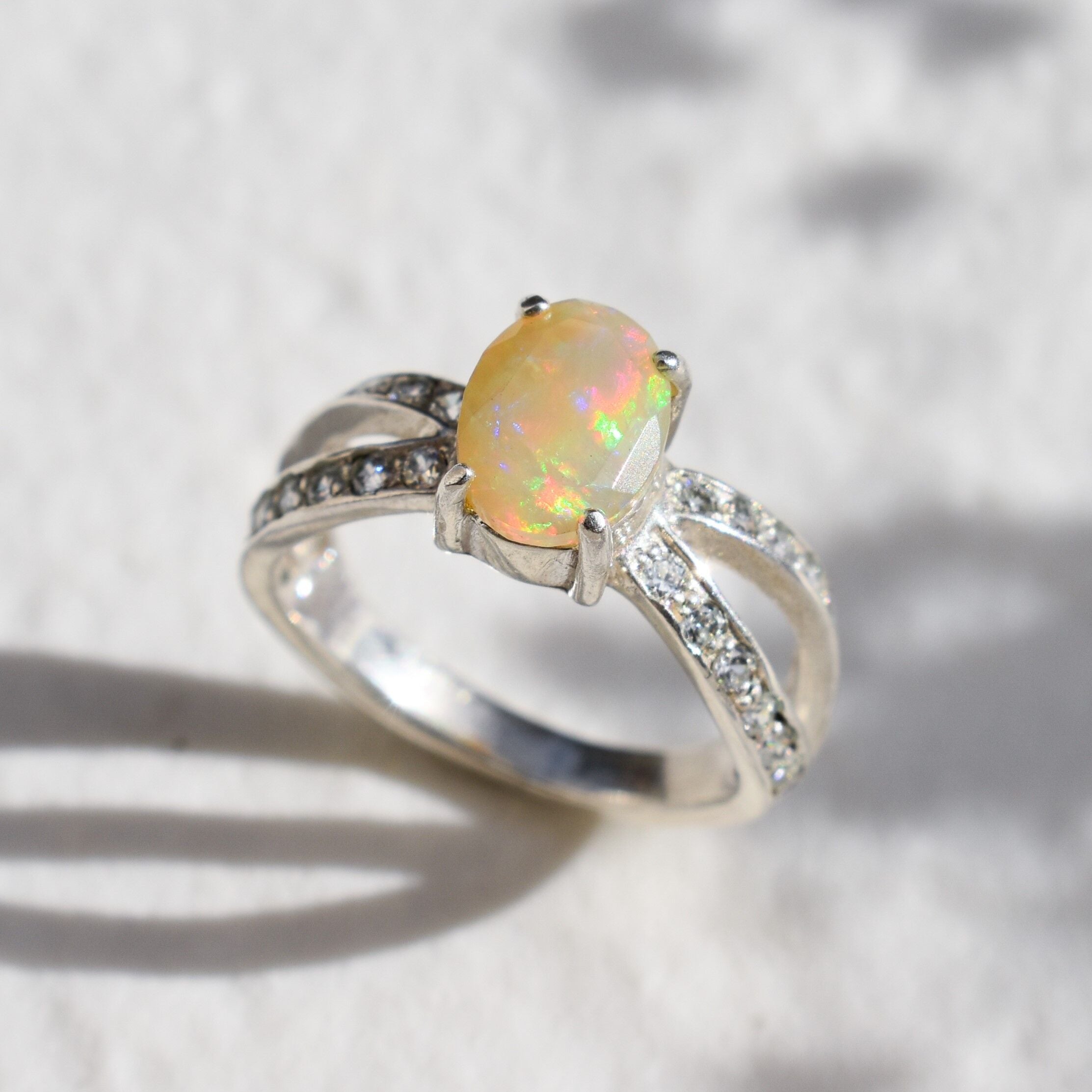 Natural Fire Opal diamond cut in a split sterling silver band with sparkling CZ Diamond accents offering vibrant energy and charm perfect as an October birthstone gift for engagements anniversaries or special celebrations.