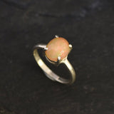 Ethiopian Fire Opal Solitaire Ring in sterling silver with a cabochon cut oval stone showing flashes of fire colors. Opal is linked to creativity, inspiration, and emotional balance, making it a meaningful October birthstone gift. A thoughtful choice for birthdays, anniversaries, promise rings, or engagements. Suitable for daily wear, weddings, and classic elegant occasions.
