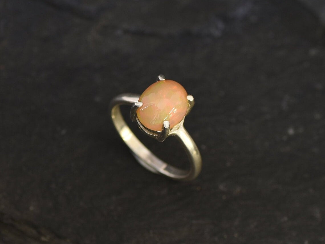 Ethiopian Fire Opal Solitaire Ring in sterling silver with a cabochon cut oval stone showing flashes of fire colors. Opal is linked to creativity, inspiration, and emotional balance, making it a meaningful October birthstone gift. A thoughtful choice for birthdays, anniversaries, promise rings, or engagements. Suitable for daily wear, weddings, and classic elegant occasions.