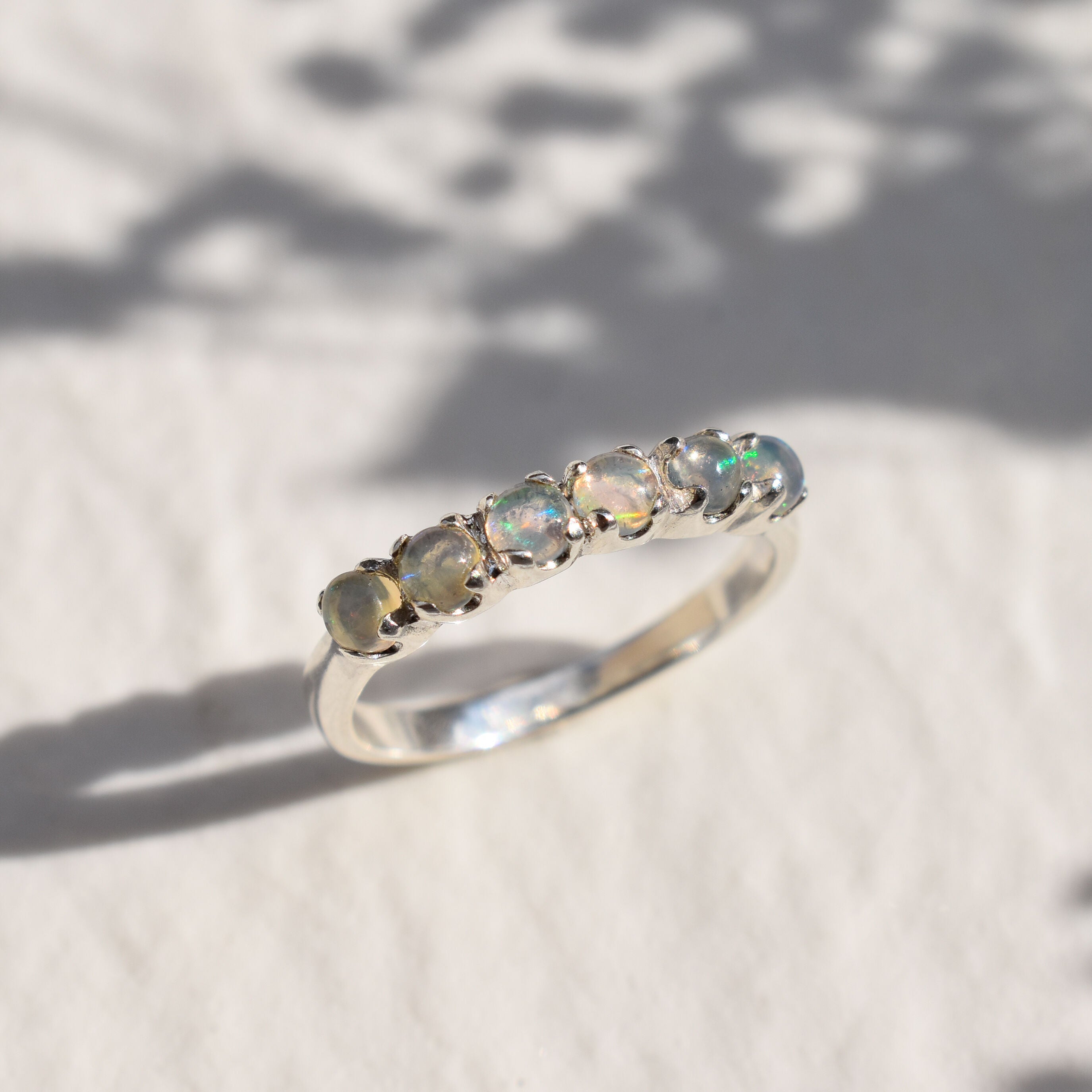 Natural Fire Opal cabochon half eternity ring in solid 925 sterling silver, designed with dainty cabochon stones for timeless elegance and flashes of fire colors. This ring highlights durability and everyday wear while being lightweight and comfortable. As the October Birthstone, Fire Opal makes a meaningful gift for birthdays, anniversaries, or special occasions. Perfect to wear at weddings, cocktail parties, and festive celebrations.