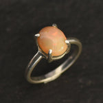 Ethiopian Fire Opal Solitaire Ring in sterling silver with a cabochon cut oval stone showing flashes of fire colors. Opal is linked to creativity, inspiration, and emotional balance, making it a meaningful October birthstone gift. A thoughtful choice for birthdays, anniversaries, promise rings, or engagements. Suitable for daily wear, weddings, and classic elegant occasions.