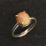 Ethiopian Fire Opal Solitaire Ring in sterling silver with a cabochon cut oval stone showing flashes of fire colors. Opal is linked to creativity, inspiration, and emotional balance, making it a meaningful October birthstone gift. A thoughtful choice for birthdays, anniversaries, promise rings, or engagements. Suitable for daily wear, weddings, and classic elegant occasions.